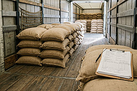 Kaffeesäcke auf Palette neben Transportpapieren als Symbol für Kaffeesteuer und Meldepflicht beim Transport durch Deutschland